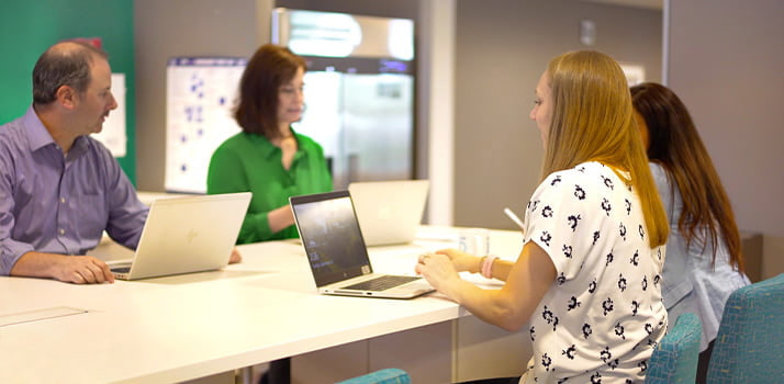 Essendant - Four Employees Work on Laptops at Conference Table